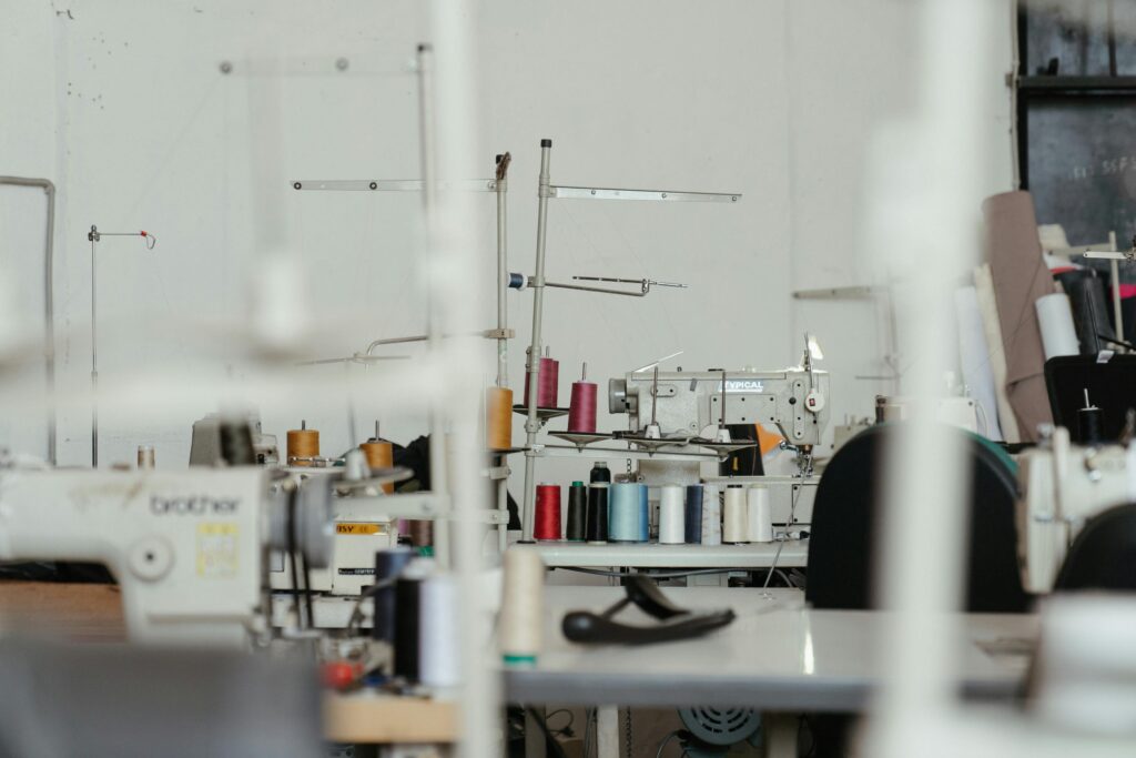 A busy sewing workshop with various sewing machines and thread spools, showcasing textile production.